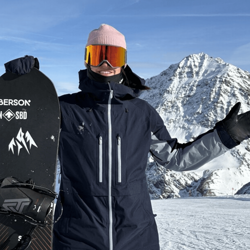 Audrey McManiman tenant une planche à neige sur une montagne enneigée.