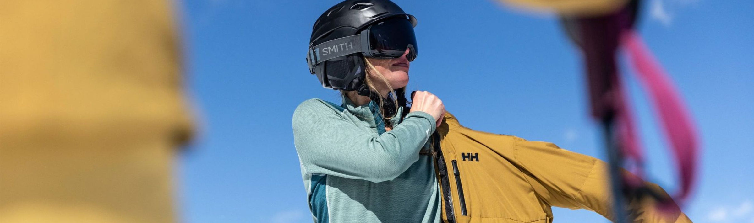 Femme en ski qui enfile son manteau de ski helly hansen