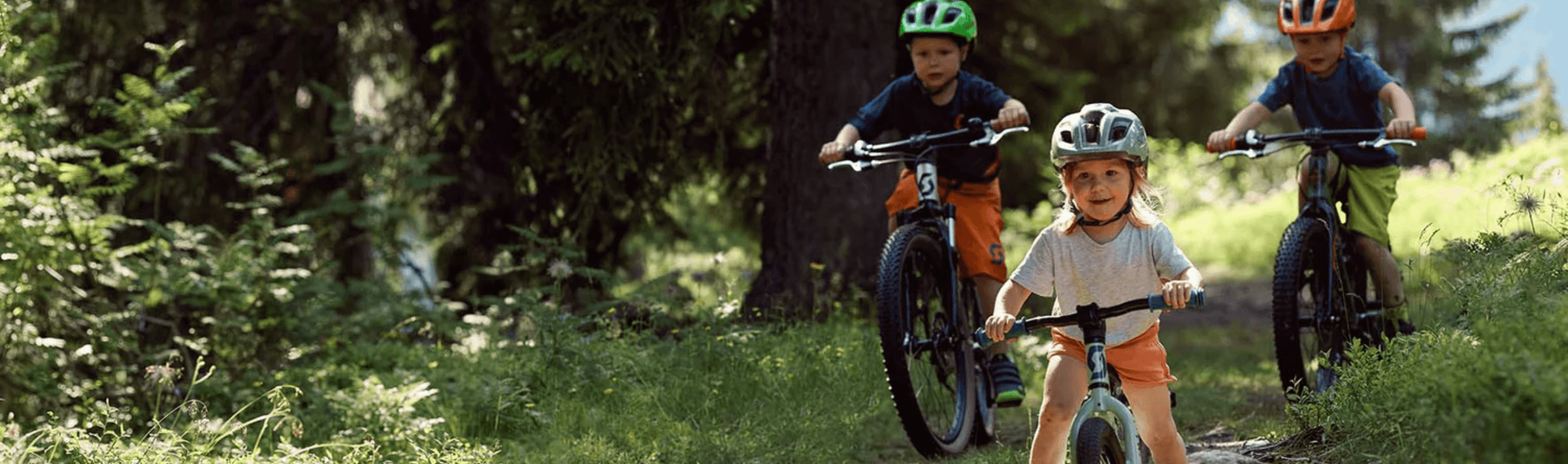 Deux jeunes garçons sur vélo de montagne et une petite fille sur un vélo pour enfants