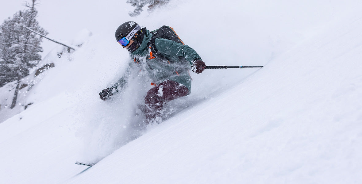Skieur de freeride dévalant une pente raide dans la poudreuse profonde.